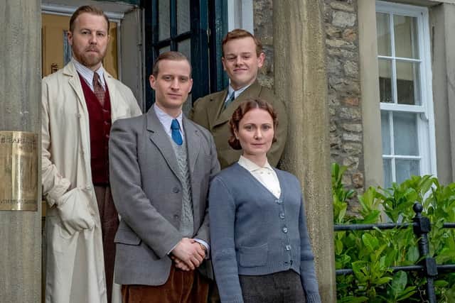 Samuel West as Siegfried Farnon, Nicolas Ralph as James Herriot, Callum Woodhouse as Tristan Farnon, and Anna Madeley as Mrs Hall, stood at the door to the vet practice (Credit: Playground Television)