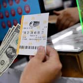A person buys a Mega Millions lottery ticket at a store on July 29, 2022 in Arlington, Virginia. Photo by OLIVIER DOULIERY/AFP via Getty Images