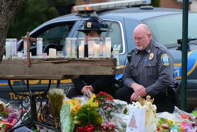 Newtown police officers pay their respects to the victims of an elementary school shooting in front of St Rose of Lima Church in Newtown, Connecticut, December 16, 2012 (Photo by EMMANUEL DUNAND/AFP via Getty Images)