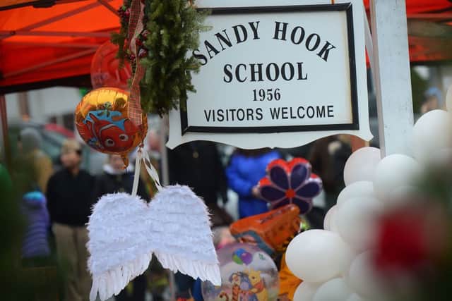 A pair of angel wings and balloons stand after being offered at a makeshift shrine to the victims of a elementary school shooting in Newtown, Connecticut, December 16, 2012 (Photo by EMMANUEL DUNAND/AFP via Getty Images)