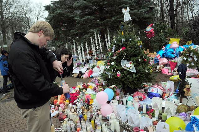People pay their respects at a makeshift shrine to the victims of an elementary school shooting in Newtown, Connecticut, December 17, 2012 (Photo by EMMANUEL DUNAND/AFP via Getty Images)