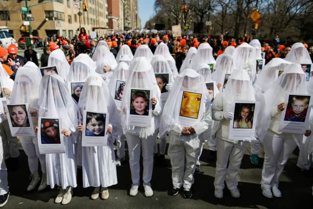People display portraits of Sandy Hook elementary school shooting victims as they take part in the March for Our Lives in New York on March 24, 2018 (Photo by EDUARDO MUNOZ ALVAREZ/AFP via Getty Images)