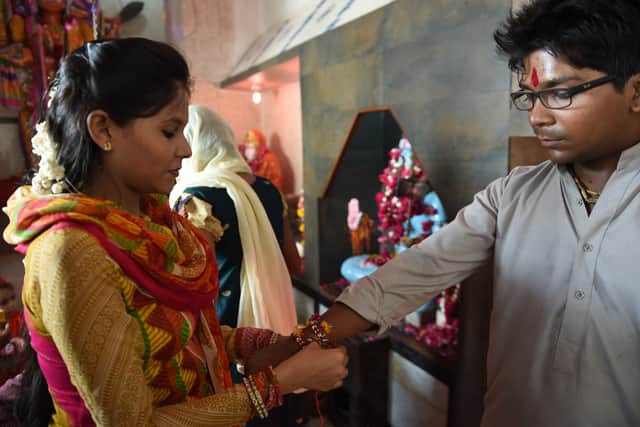 A Pakistani Hindu sister ties a 'rakhi' - sacred thread - onto the wrist of her brother during the Hindu festival Raksha Bandhan