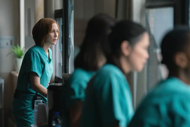 Vera Farmiga as Dr Anna Pou in Five Days at memorial. She and a number of others in blue surgical scrubs stand watching the windows (Credit: Apple TV+)