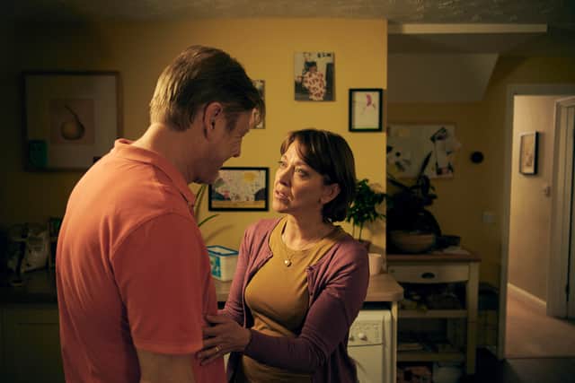 Sean Bean as Ian and Nicola Walker as Emma. They’re stood in their kitchen, facing one another in a low yellow light; Ian is turned away from the viewer and Emma has a hand on Ian’s abdomen (Credit: BBC / The Forge / Rory Mulvey)