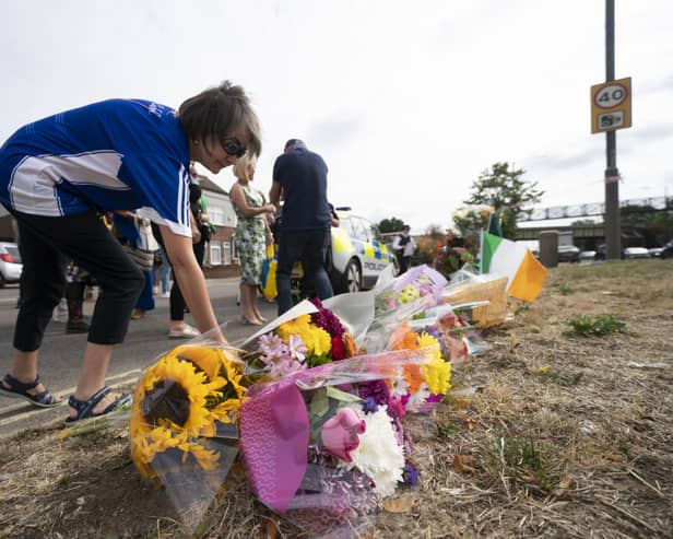 A woman lays flowers on Western Avenue Frontage Road in Greenford, Ealing, west London, where members of the Irish community gathered to pray and lay flowers in tribute to Thomas O'Halloran, 87, who had been riding a mobility scooter on Cayton Road, Greenford, when he was stabbed to death on Tuesday. Picture date: Sunday August 21, 2022.