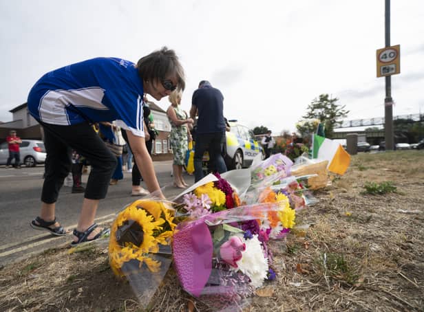 <p>A woman lays flowers on Western Avenue Frontage Road in Greenford, Ealing, west London, where members of the Irish community gathered to pray and lay flowers in tribute to Thomas O'Halloran, 87, who had been riding a mobility scooter on Cayton Road, Greenford, when he was stabbed to death on Tuesday. Picture date: Sunday August 21, 2022.</p>