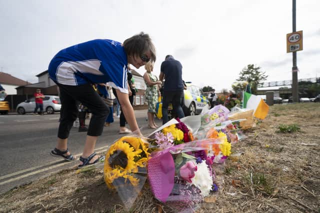 A woman lays flowers on Western Avenue Frontage Road in Greenford, Ealing, west London, where members of the Irish community gathered to pray and lay flowers in tribute to Thomas O'Halloran, 87, who had been riding a mobility scooter on Cayton Road, Greenford, when he was stabbed to death on Tuesday. Picture date: Sunday August 21, 2022.