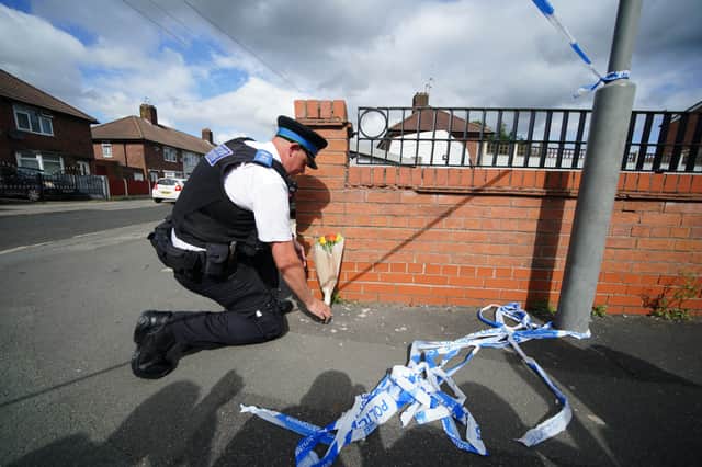 A police officer lays flowers near to the scene in Kingsheath Avenue, Knotty Ash, Liverpool, where a nine-year-old girl has been fatally shot. Credit: PA