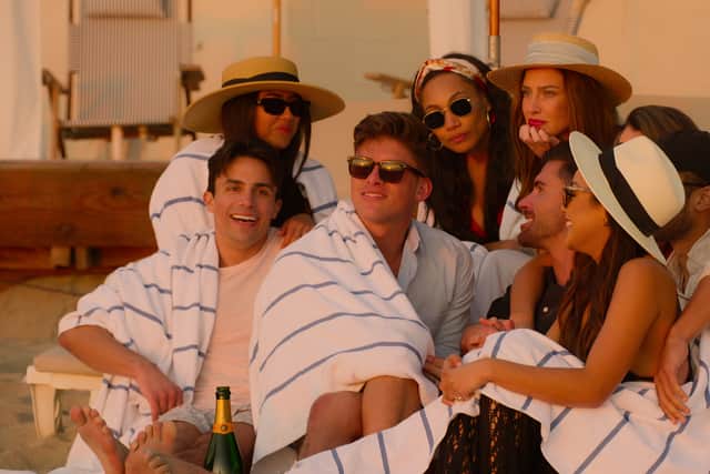 Selling The OC cast (L to R) Gio Helou, Kayla Carmona, Austin Victoria, Brandi Marshall, Polly Brindle, Tyler Stanaland and Lauren Brito cuddle up on the beach (Pic: Netflix)