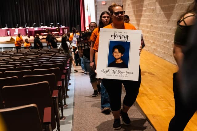 Attendees hold signs as they walk out of a Uvalde Consolidated Independent School District Board special meeting to consider the firing of Police Chief Pete Arredondo. Credit: Jordan Vonderhaar/Getty Images