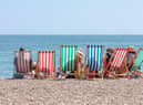 Rear View of Group of People Seated in Six Striped Deckchairs at the Seaside on a Bright Sunny Summer Day (Ian - stock.adobe.com)