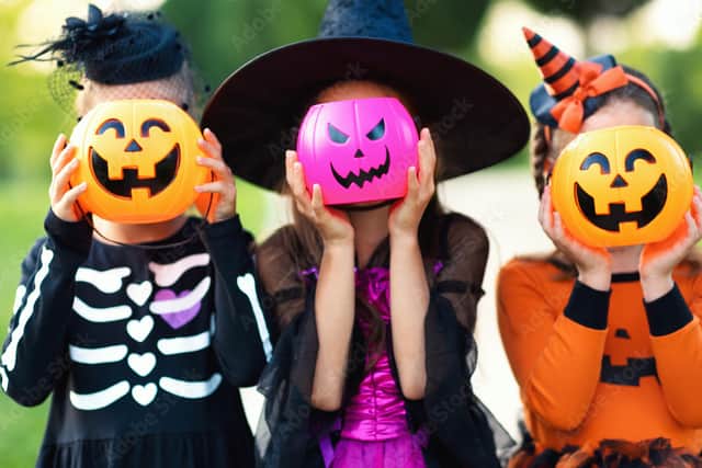 Happy Halloween! funny children in carnival costumes hide their heads behind buckets pumpkins outdoors. (JenkoAtaman - stock.adobe.com)