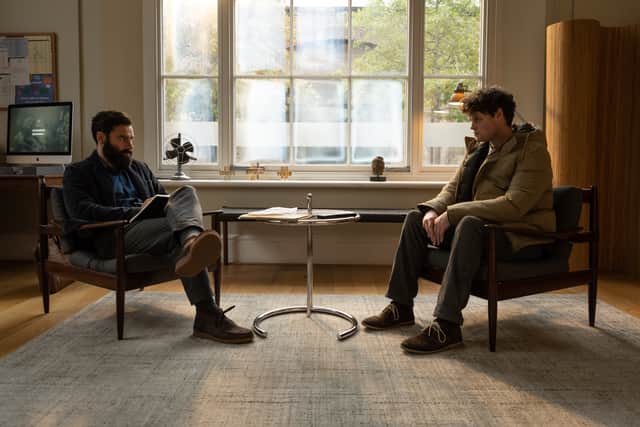 Aidan Turner as Doctor Joe O’Loughlin and Bobby Schofield as Bobby Moran, sat across from one another during a therapy session. A window in the middle of them casts light onto the floor (Credit: ITV/World Productions)