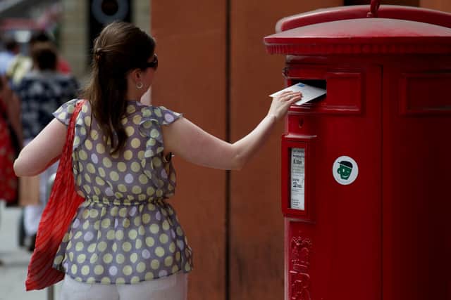 A woman posts a letter in a Royal Mail post box in London (Pic: AFP via Getty Images)