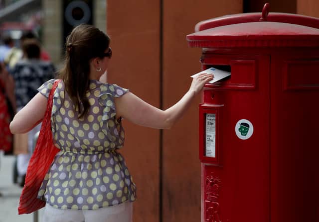 A woman posts a letter in a Royal Mail post box in London (Pic: AFP via Getty Images)
