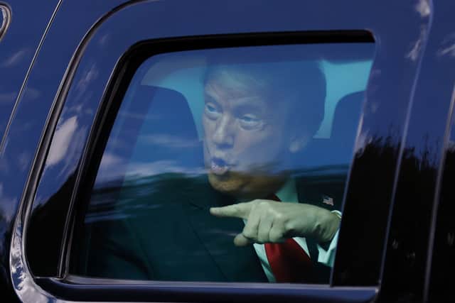 Donald Trump waves to supporters lined along on the route to his Mar-a-Lago estate on January 20, 2021 in West Palm Beach, Florida (Photo by Michael Reaves/Getty Images)