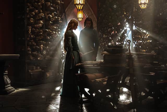 Morfydd Clark as Galadriel and Lloyd Owen as Elendil, examining scrolls in darkness. Light seeps through the gaps in the bookcase behind them (Credit: Matt Grace/Prime Video)