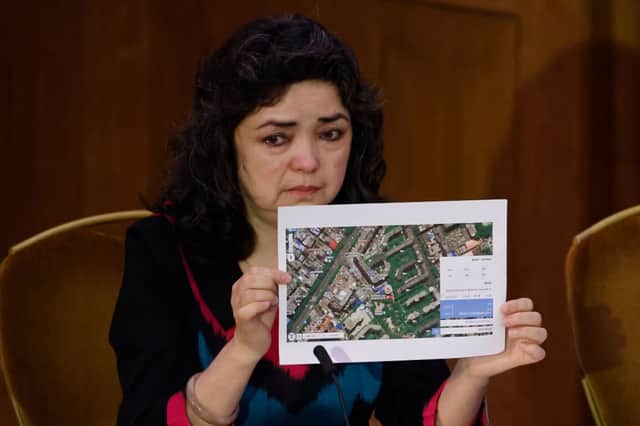 Witness Uyghur teacher Qelbinur Sidik holds up a photograph of the hospital where she says she underwent a forced sterilization procedure on the first day of hearings at the “Uyghur Tribunal”. Credit: TOLGA AKMEN/AFP via Getty Images