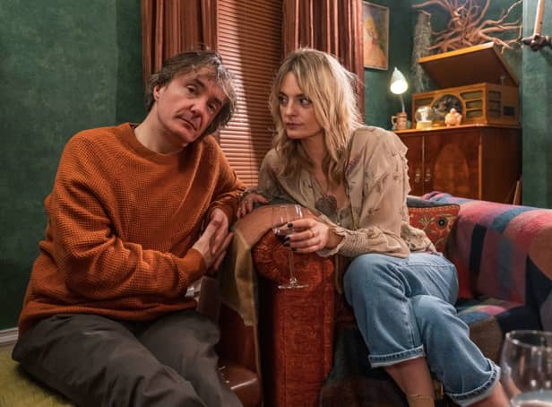 <p>Dylan Moran as Dan and Morgana Robinson as Carla in Stuck. They’re leaning towards each other, and Carla is holding a glass of wine (Credit: BBC/Chris Barr)</p>