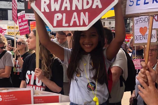 A young girl holds a sign at the protests against the Rwanda asylum policy in London. Credit: @Care4Calais on Twitter