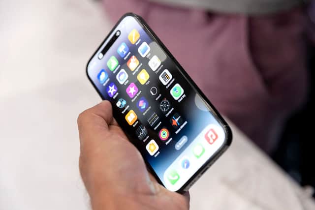 An Apple associate holds one of the new iPhone Pros during a launch event for new products at Apple Park in Cupertino, California, on September 7, 2022 (Photo by BRITTANY HOSEA-SMALL/AFP via Getty Images)