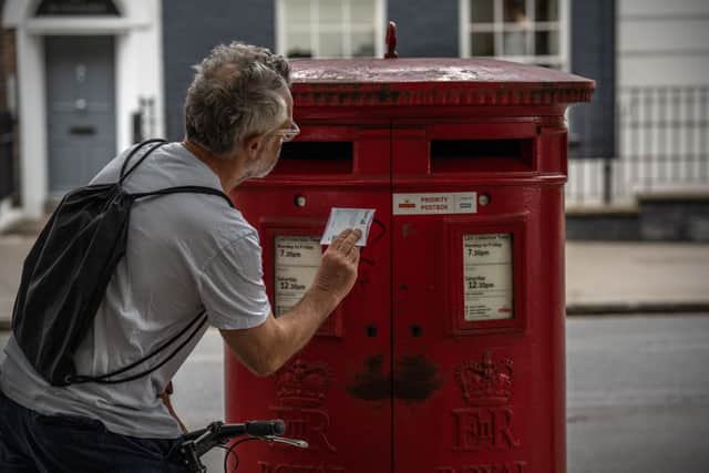 A man posts a letter in a Royal Mail postbox on June 30, 2022 in London, England (Photo by Carl Court/Getty Images)