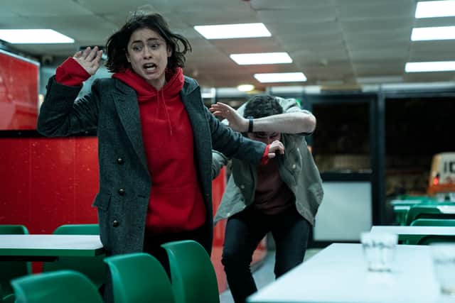 Rosa Salazar as Katie McConnell and Gavin Drea as Steffan Bridges in Wedding Season. They’re running throug a diner, looking panicked (Credit: Luke Varley/Disney+)