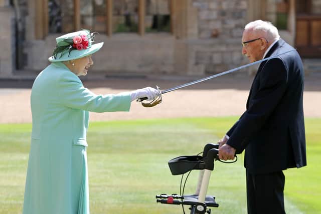Queen Elizabeth II uses the sword that belonged to her father, George VI as she confers the Honour of Knighthood on 100-year-old WWII veteran Captain Tom Moore at Windsor Castle. Credit: Getty Images