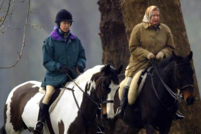 Queen Elizabeth II (R) and her daughter Princess Anne (L) ride in the grounds of Windsor Castle 02 April 2002.  (Photo credit: ADRIAN DENNIS/AFP via Getty Images)