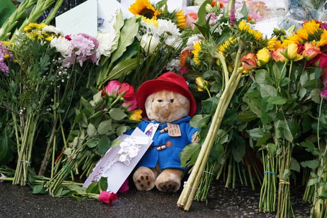 Floral tributes and a Paddington bear teddy are laid at the gates of Balmoral in Scotland. The Queen memorably appeared with Paddington in a sketch for her Platnium Party at the Palace concert in June. Picture: PA.