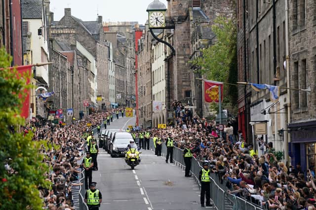 The hearse carrying the coffin of Queen Elizabeth II, draped with the Royal Standard of Scotland, passes along the Canongate (PA)
