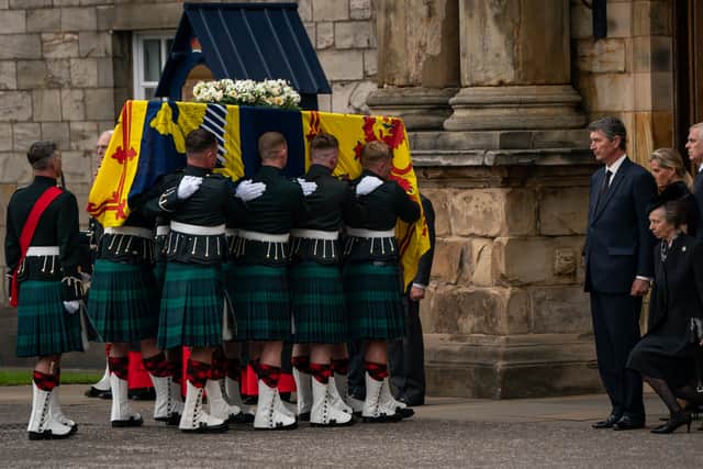 The Princess Royal curtseys the coffin of Queen Elizabeth II, draped with the Royal Standard of Scotland, as it arrives at Holyroodhouse