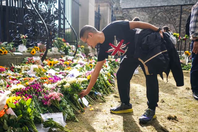 A man is seen laying flowers in remembrance of the late Queen Elizabeth II outside the Palace of Holyroodhouse on September 12, 2022 in Edinburgh, Scotland. (Photo by Peter Summers/Getty Images)