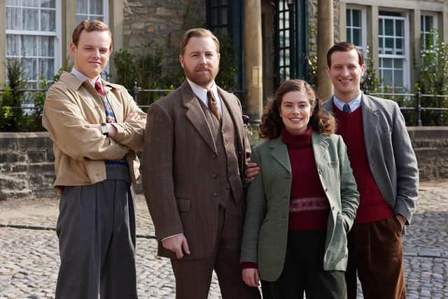 Callum Woodhouse as Tristan Farnon, Samuel West as Siegfried Farnon, Rachel Shenton as Helen Alderson, and Nicholas Ralph as James Herriot. They're stood outside on a cobbled street, the vet practice in the distance behind them (Credit: Helen Williams / Playground Entertainment)
