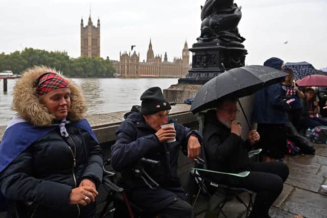 Members of the public queue in the rain along opposite the Palace of Westminster (Pic: AFP via Getty Images)
