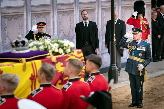 King Charles III, salutes as the bearer party carry the coffin of his mother, Queen Elizabeth II, into Westminster Hall.