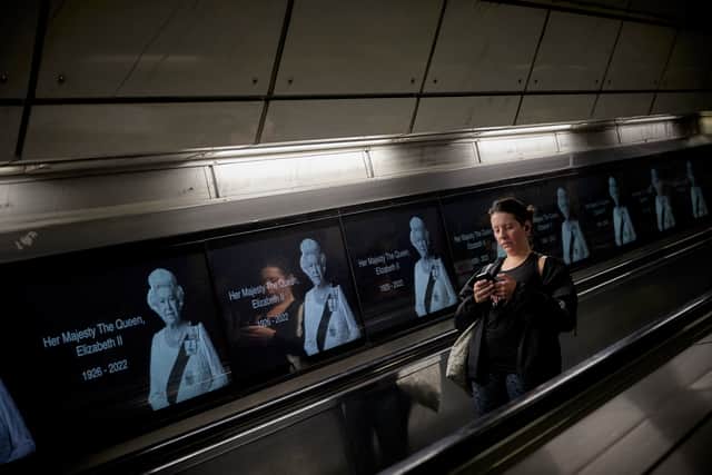 A passenger travelling on the London Underground passes by advertising boards commemorating Queen Elizabeth II (Pic: Getty Images)
