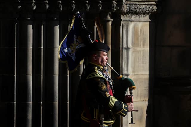 EDINBURGH, SCOTLAND  - SEPTEMBER 13: A piper walks in the Queen's coffin procession out of the St Giles' Cathedral on September 13, 2022 in Edinburgh, Scotland. The coffin carrying Her Majesty Queen Elizabeth II leaves St Giles Church travelling to Edinburgh Airport where it will be flown to London and transferred to Buckingham Palace by road. Queen Elizabeth II died at Balmoral Castle in Scotland on September 8, 2022, and is succeeded by her eldest son, King Charles III. (Photo by Kai Pfaffenbach - WPA Pool/Getty Images)