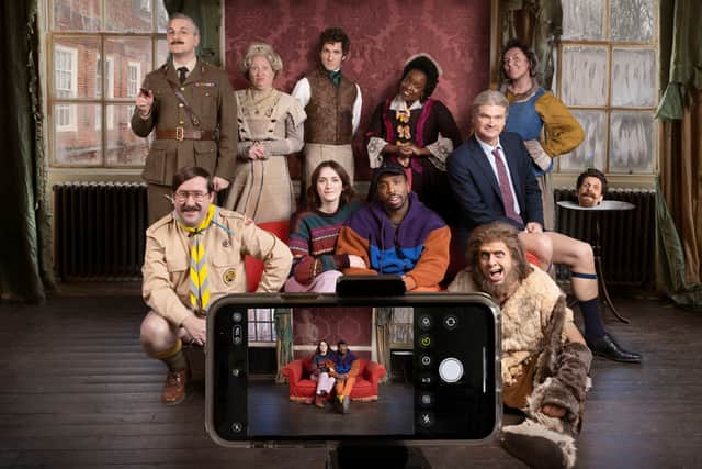A promotional image for Ghosts S4, depicting a mobile phone taking a picture of Alison, Mike, and the Ghosts - who can’t be seen through the phone screen (Credit: BBC/Monumental Pictures/Guido Mandozzi)