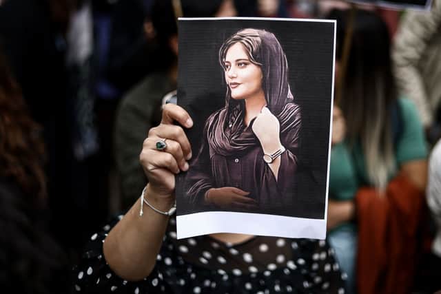 A protester in Brussels holds a portrait of Mahsa Amini. (Credit: Getty Images)