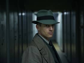 Volker Bruch as Inspector Gereon Rath in Babylon Berlin, stood in a dark alley with a fedora angled over his face (Credit: Frédéric Batier/X Filme)