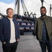 Comedians Rob Beckett and Romesh Ranganathan in DNA Journey, stood in front of a pirate ship (Credit: ITV)
