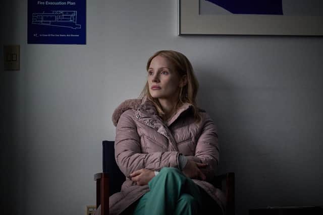 Jessica Chastain as Amy Loughren in The Good Nurse, wearing a pink coat over green surgical scrubs (Credit: JoJo Whilden/Netflix)
