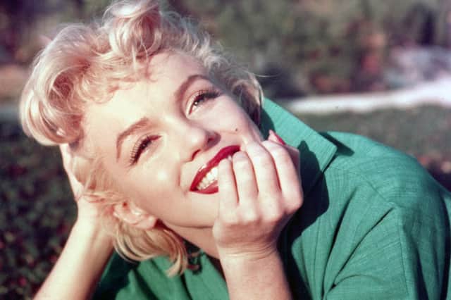 ctress Marilyn Monroe poses for a portrait laying on the grass in 1954 in Palm Springs, California
