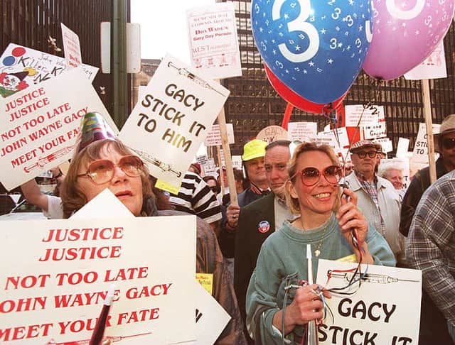 Some of the 5,000 demonstrators supporting the scheduled execution of serial killer John Wayne Gacy hold balloons and wear party hats as they march in a Gacy Day Parade 09 May 1994 in Chicago (Photo by EUGENE GARCIA/AFP via Getty Images)