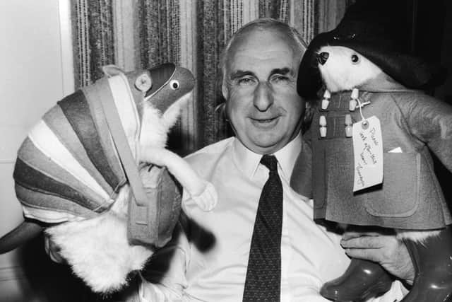 British children's book author Michael Bond stands with stuffed animal toys of his characters Paddington Bear and J.D. Polson the Armadillo, June 27, 1981