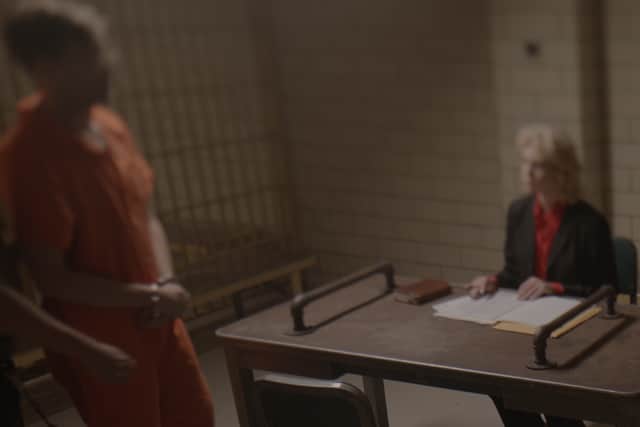 A blurry image of a man in a prison jumpsuit, being lead to a sitdown interview (Credit: Netflix)