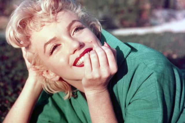 Actress Marilyn Monroe poses for a portrait laying on the grass in 1954 in Palm Springs, California. 