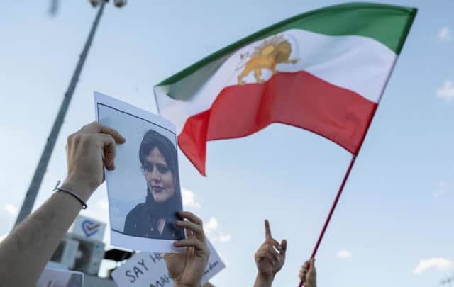 One protester holds a photo of Mahsa Amini as another waves Iran’s former flag during a demonstration against the Iranian regime and in support of Iranian women. Credit: Getty Images